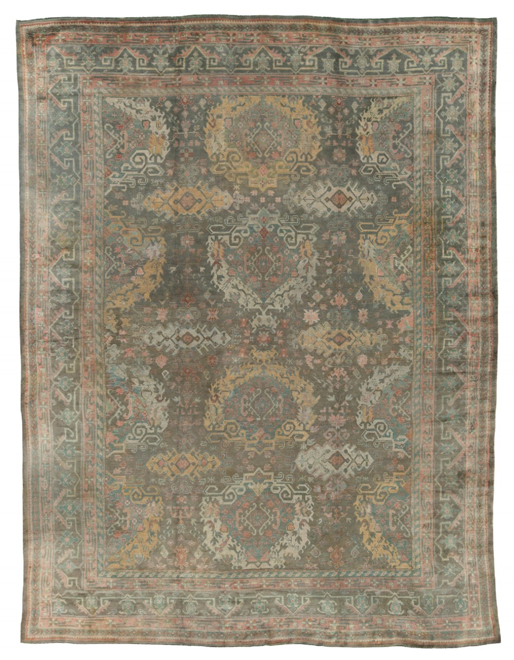 An antique hand-knotted Ushak wool carpet featuring a muted grey-green field adorned with central medallions, floral motifs, and multi-layered geometric borders in soft terracotta, pink, and gold tones.