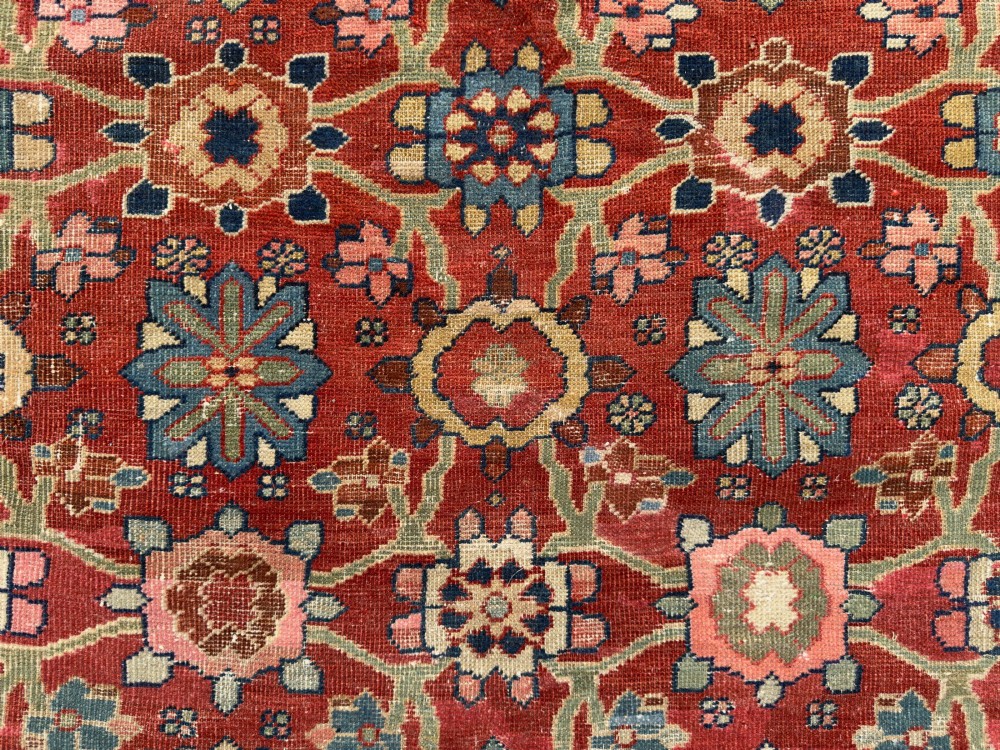 An antique Sultanabad hand-knotted wool carpet featuring an all-over repeating geometric floral pattern on a terracotta red field with a dark blue patterned border. View II