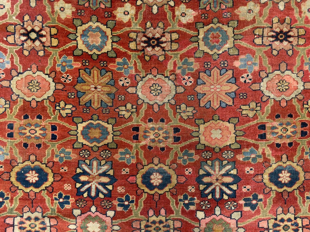 An antique Sultanabad hand-knotted wool carpet featuring an all-over repeating geometric floral pattern on a terracotta red field with a dark blue patterned border. View VII
