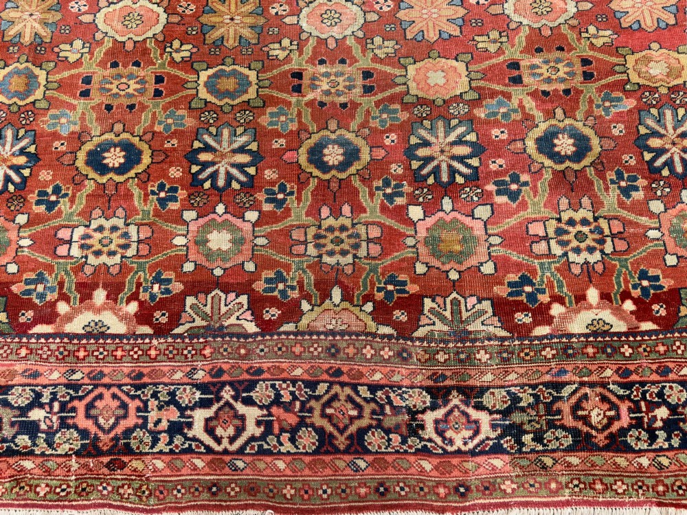 An antique Sultanabad hand-knotted wool carpet featuring an all-over repeating geometric floral pattern on a terracotta red field with a dark blue patterned border. View VIII