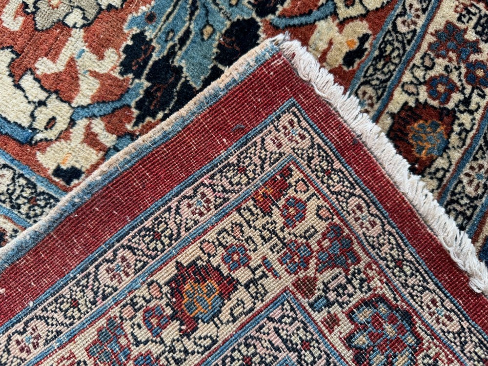 An antique Persian Tabriz wool carpet featuring a complex terracotta and navy central medallion on an ivory field with layered floral borders. View II