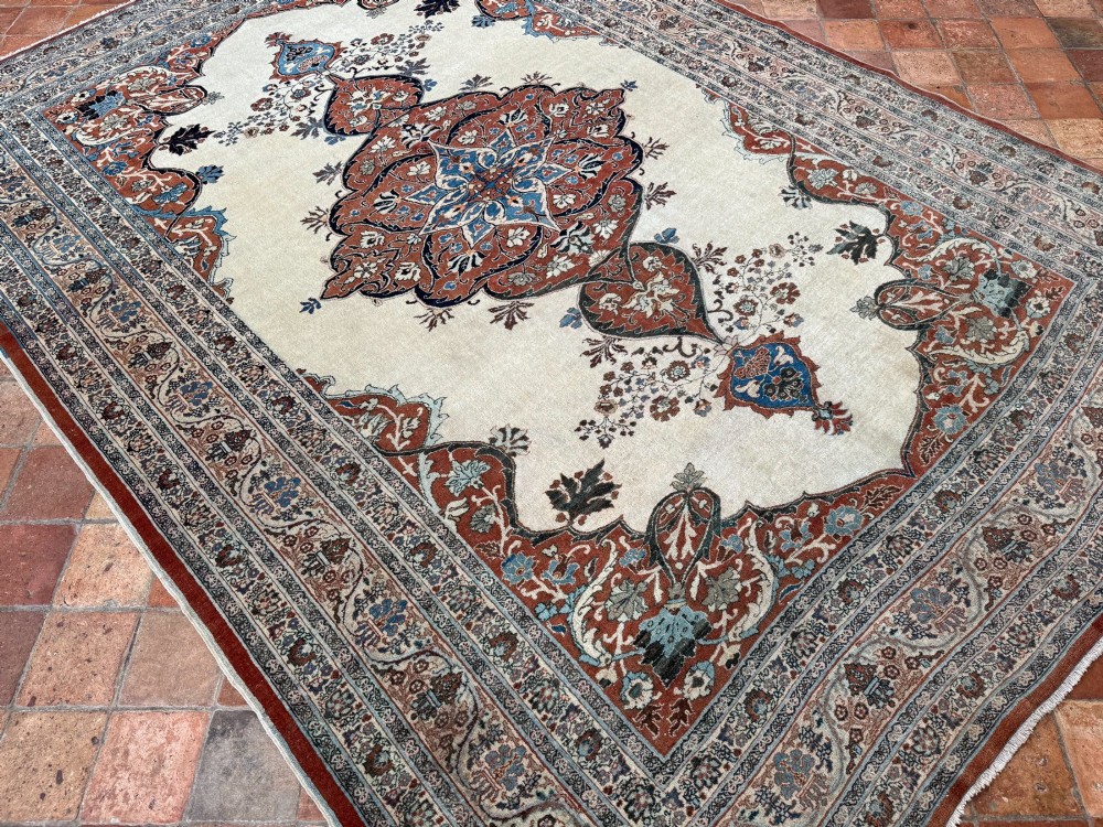 An antique Persian Tabriz wool carpet featuring a complex terracotta and navy central medallion on an ivory field with layered floral borders. View III