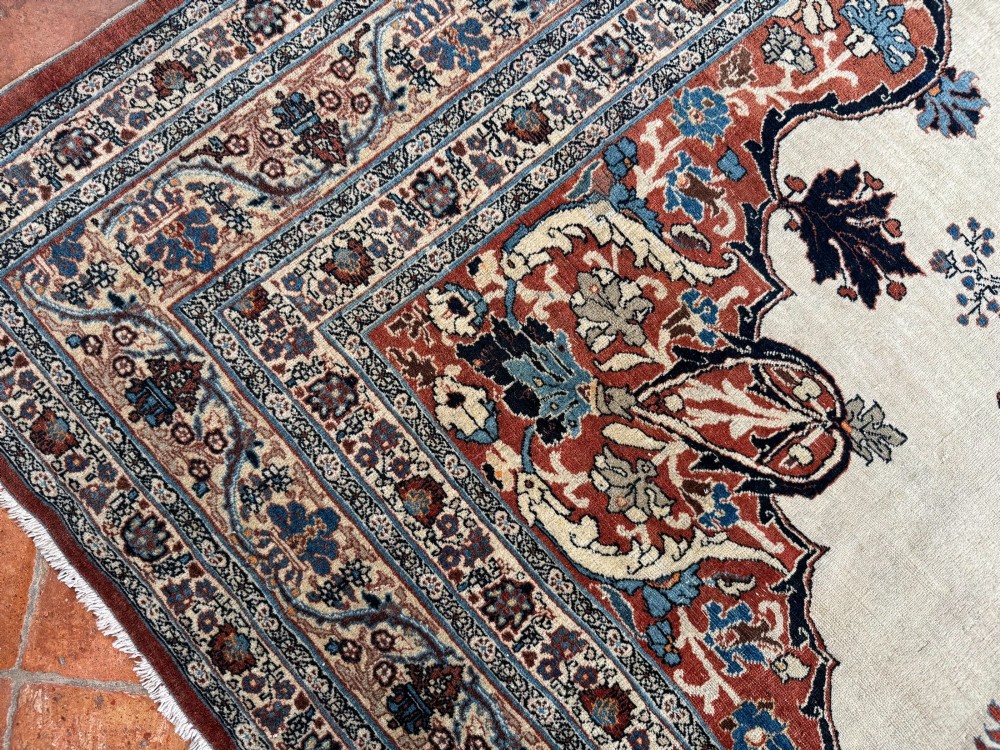 An antique Persian Tabriz wool carpet featuring a complex terracotta and navy central medallion on an ivory field with layered floral borders. View V