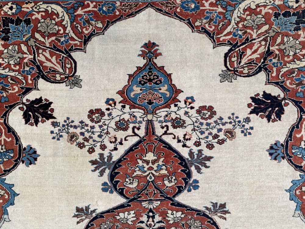 An antique Persian Tabriz wool carpet featuring a complex terracotta and navy central medallion on an ivory field with layered floral borders. View VI