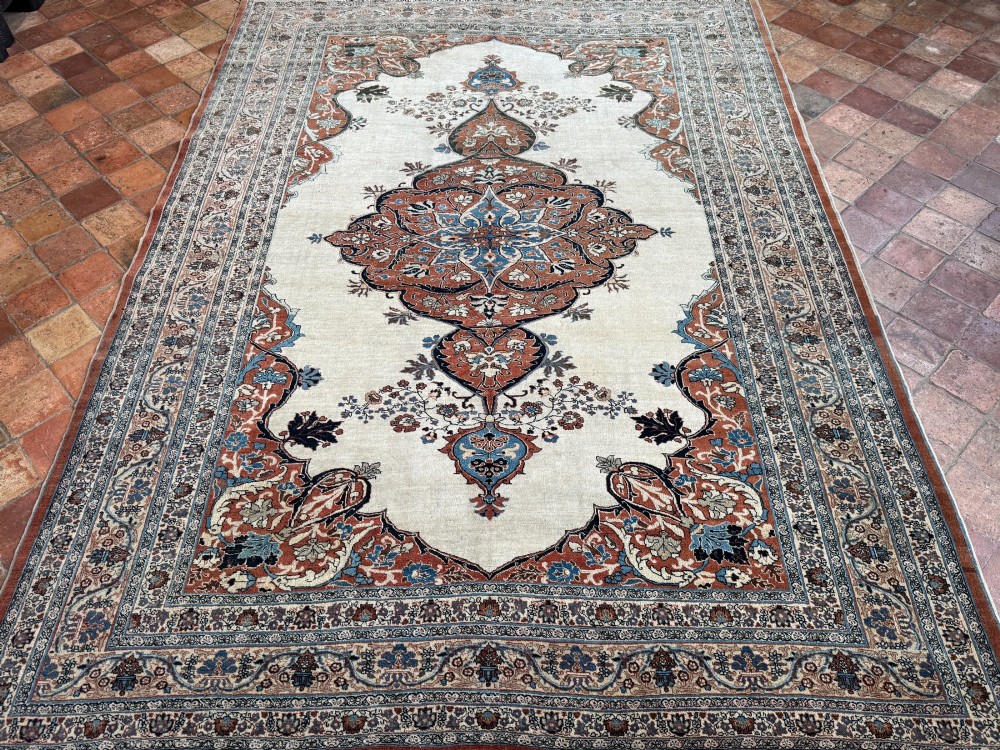 An antique Persian Tabriz wool carpet featuring a complex terracotta and navy central medallion on an ivory field with layered floral borders. View VII