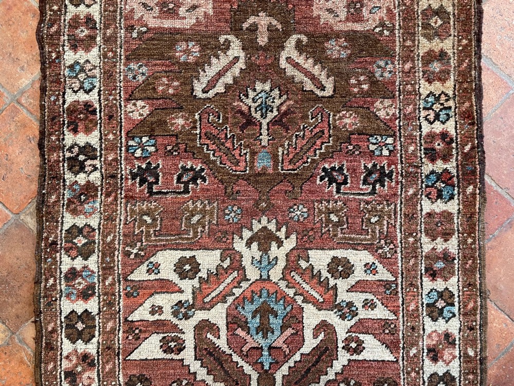 An antique Bakshaish hand-knotted wool runner rug featuring geometric tribal medallions in terracotta red, indigo blue, cream, and brown along a long narrow field with decorative borders. View VIII