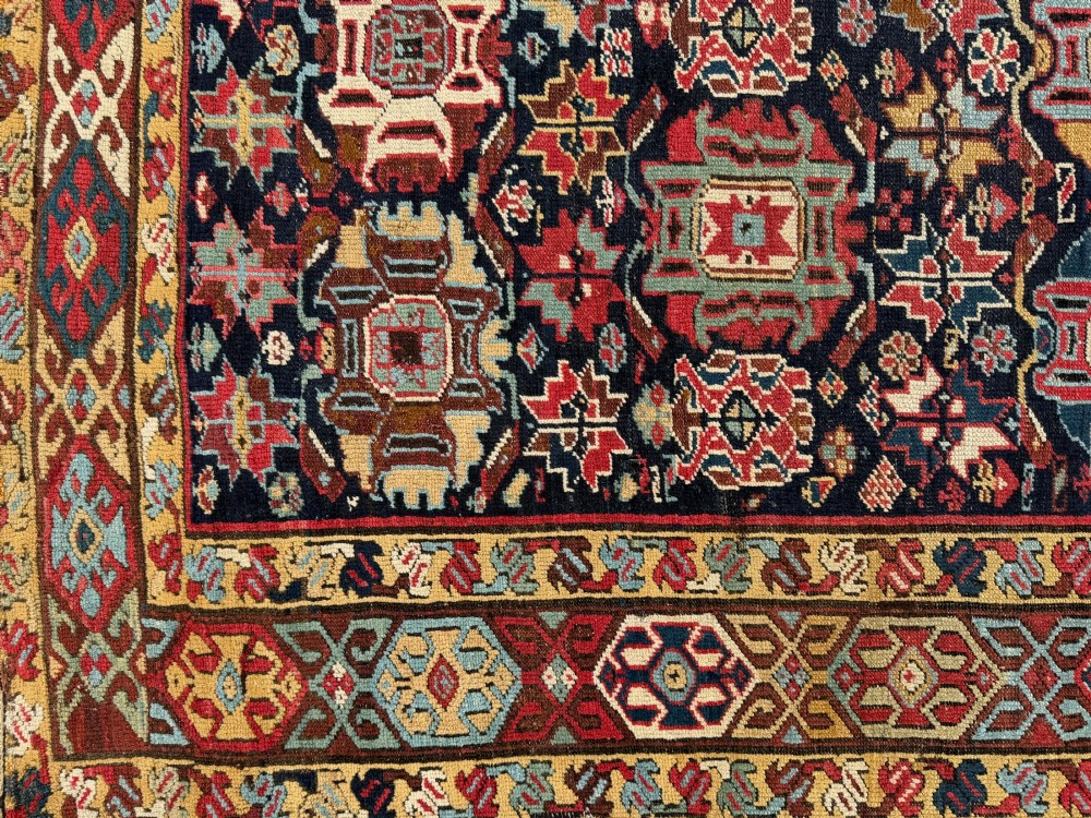 An elongated antique hand-knotted Caucasian Kuba Kelleh rug with a navy blue field featuring geometric repeating medallions framed by patterned multicoloured borders. View VIII
