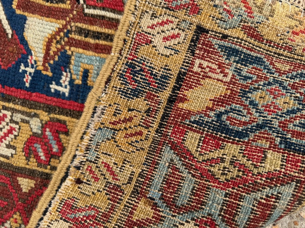 An elongated antique hand-knotted Caucasian Kuba Kelleh rug with a navy blue field featuring geometric repeating medallions framed by patterned multicoloured borders. View XI