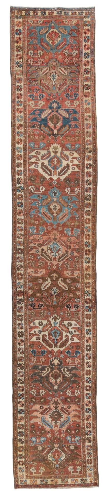 An antique Bakshaish hand-knotted wool runner rug featuring geometric tribal medallions in terracotta red, indigo blue, cream, and brown along a long narrow field with decorative borders.