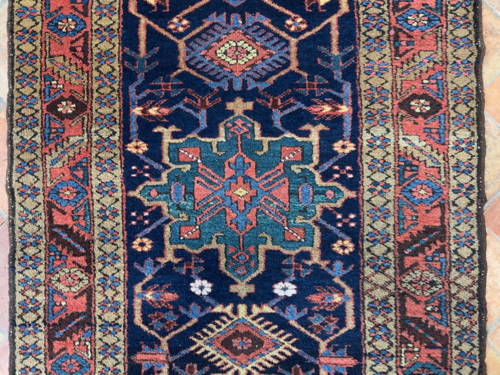 An antique Karaja hand-knotted wool runner featuring geometric blue and terracotta medallions on a dark navy field. View III