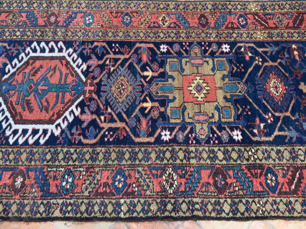 An antique Karaja hand-knotted wool runner featuring geometric blue and terracotta medallions on a dark navy field. View V