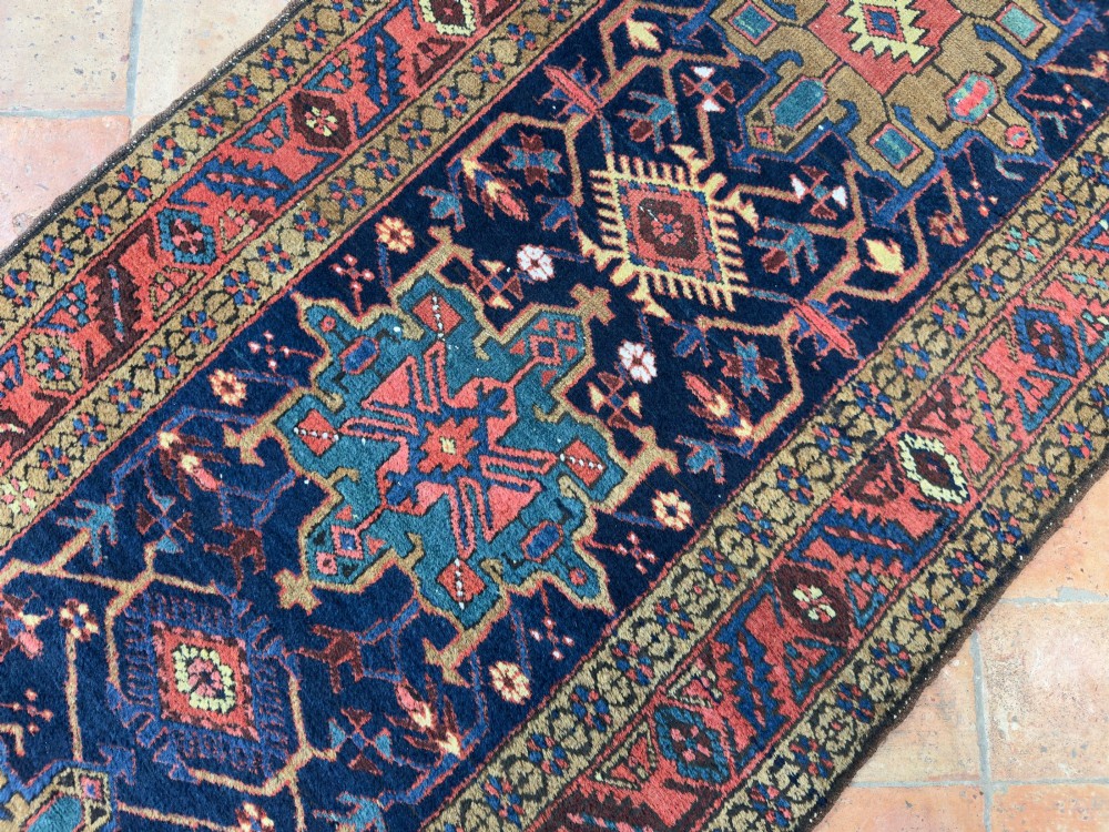 An antique Karaja hand-knotted wool runner featuring geometric blue and terracotta medallions on a dark navy field. View VI