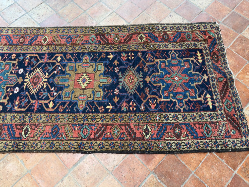 An antique Karaja hand-knotted wool runner featuring geometric blue and terracotta medallions on a dark navy field. View VII