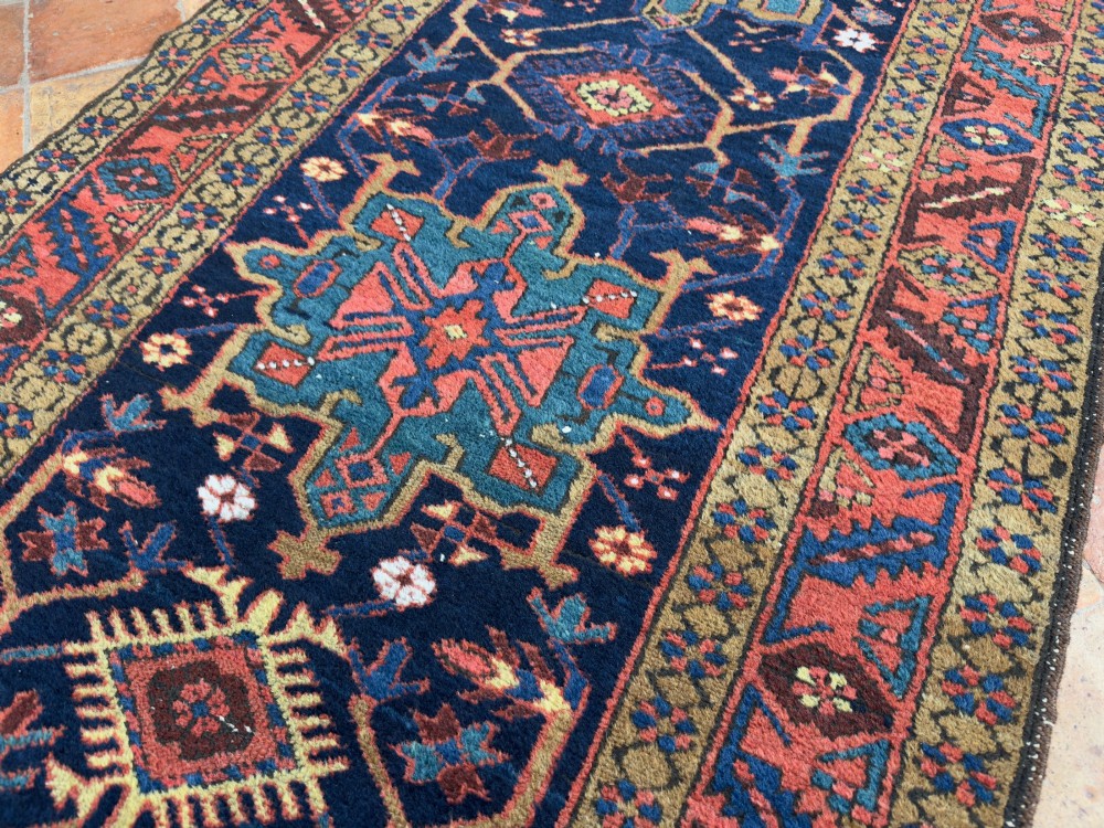 An antique Karaja hand-knotted wool runner featuring geometric blue and terracotta medallions on a dark navy field. View IX
