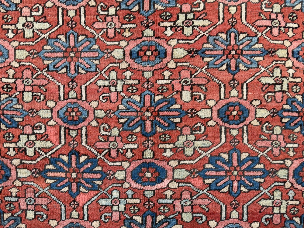 A hand-knotted antique Heriz wool carpet featuring a repeating geometric star motif on a terracotta red field framed by a wide navy blue patterned border. View XI