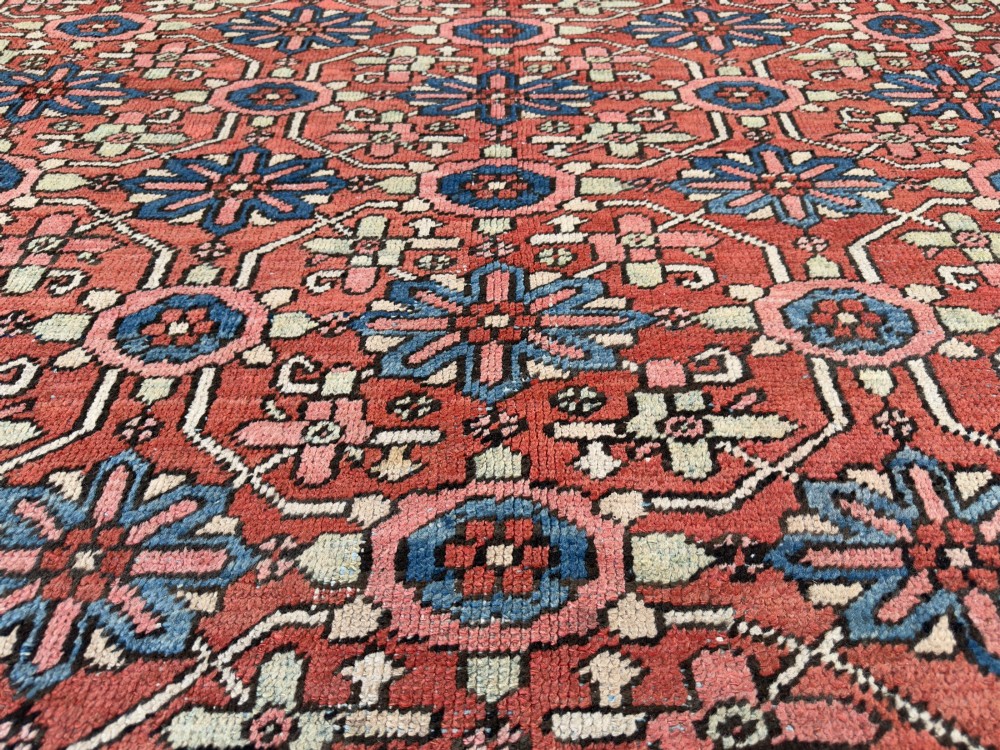 A hand-knotted antique Heriz wool carpet featuring a repeating geometric star motif on a terracotta red field framed by a wide navy blue patterned border. View XII