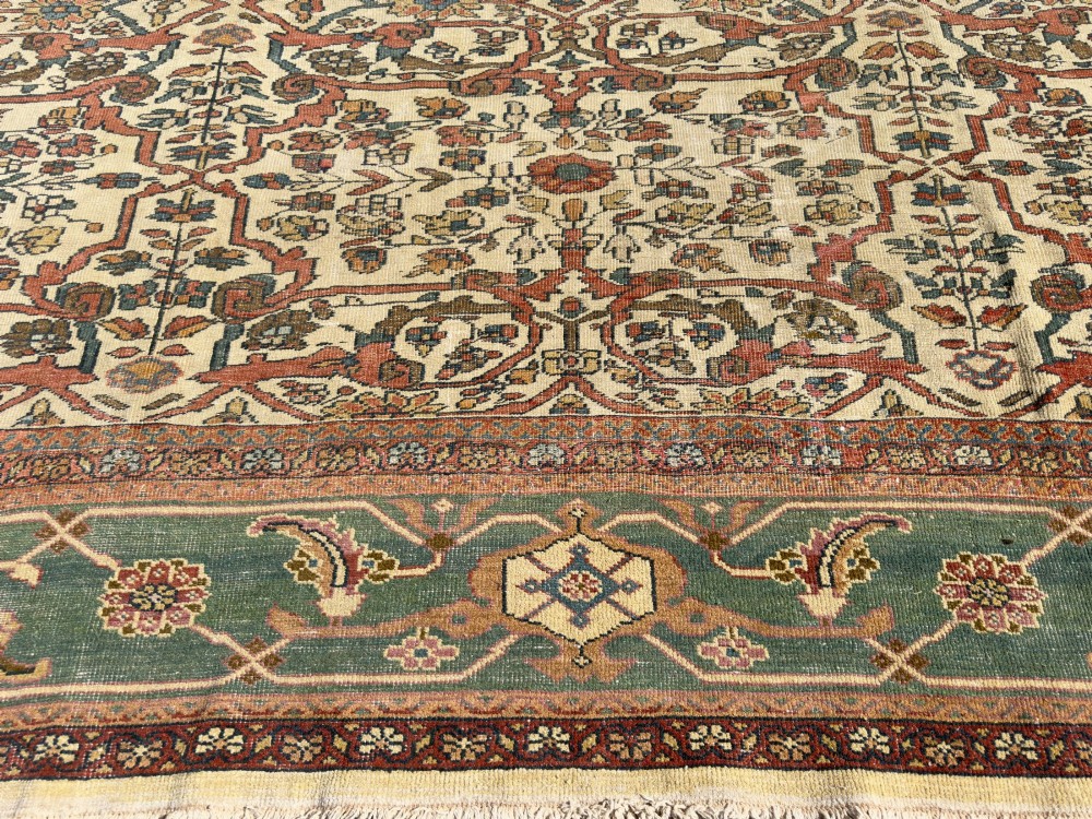 An antique Persian Sultanabad wool carpet featuring a cream field with an intricate floral lattice motif and a wide teal green border. View II