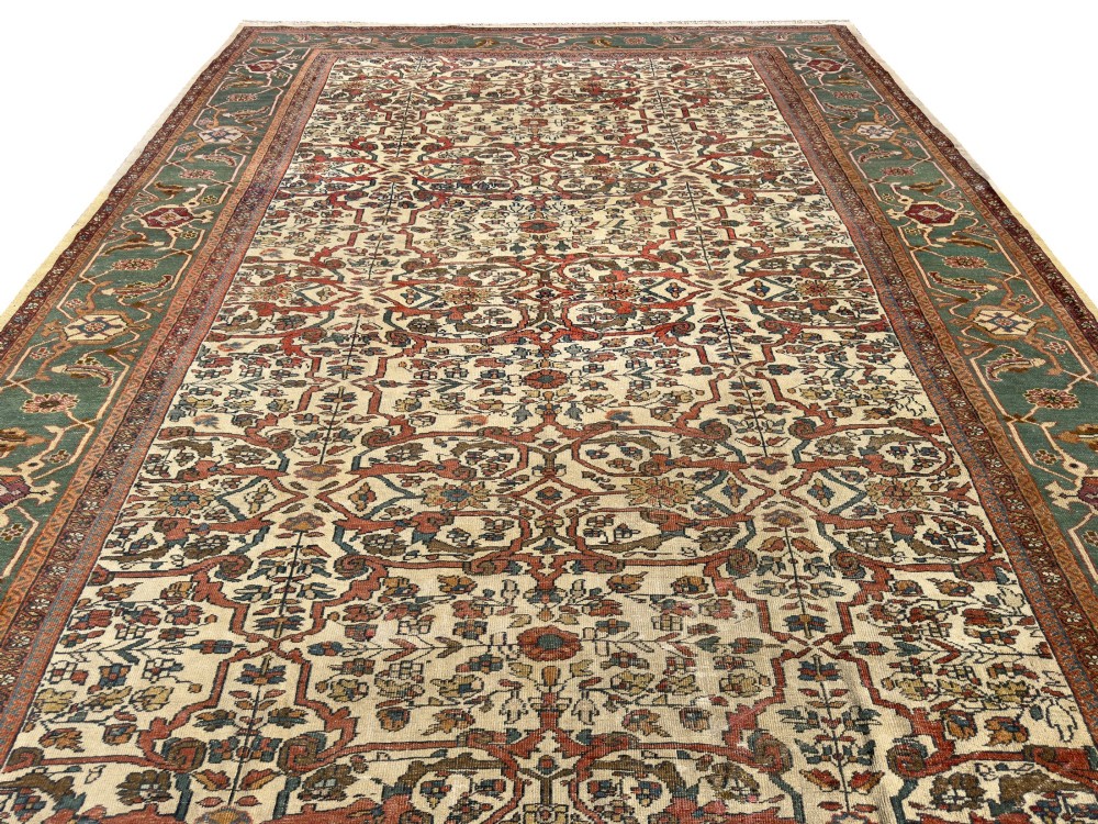 An antique Persian Sultanabad wool carpet featuring a cream field with an intricate floral lattice motif and a wide teal green border. View III
