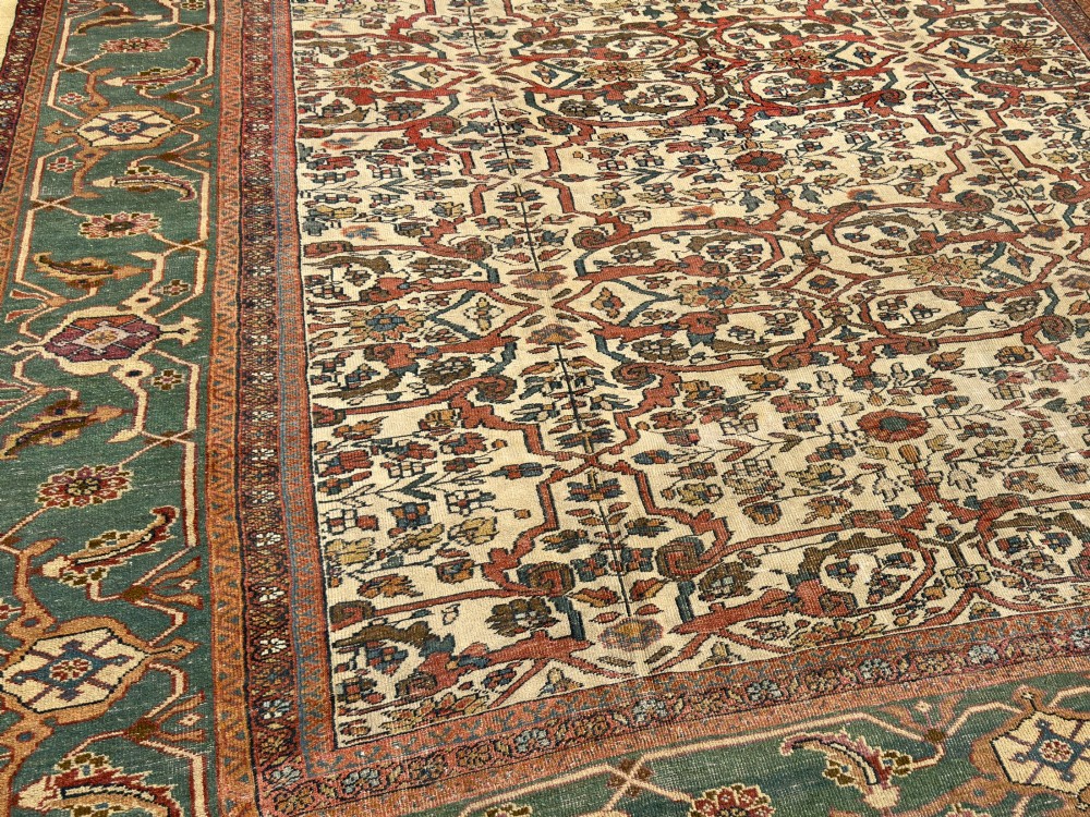 An antique Persian Sultanabad wool carpet featuring a cream field with an intricate floral lattice motif and a wide teal green border. View IV