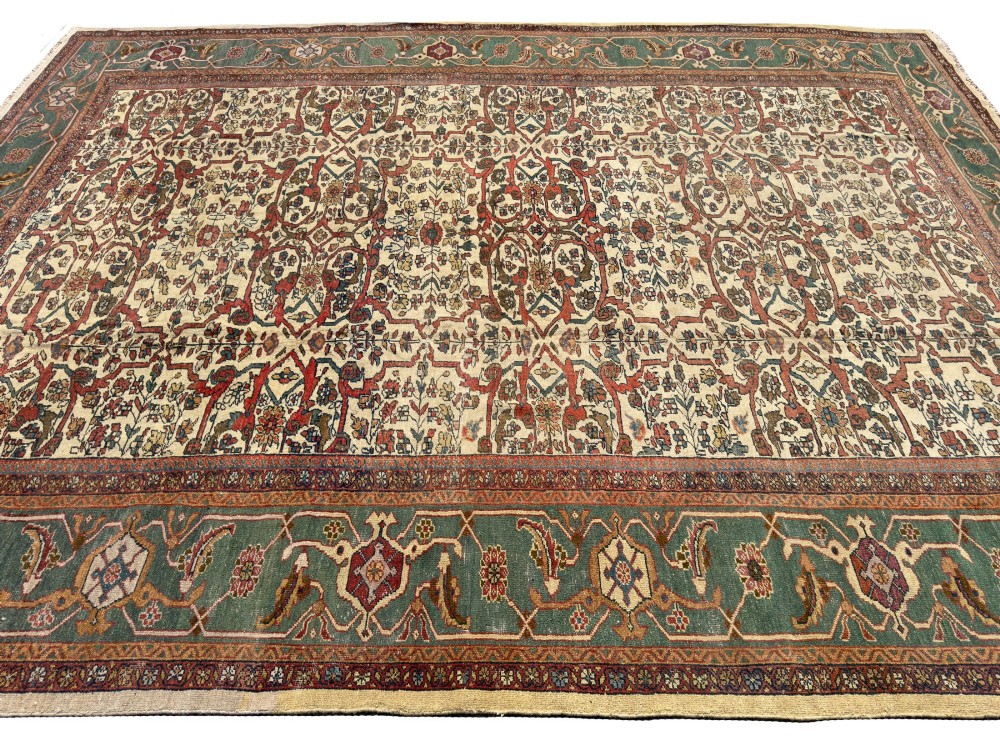 An antique Persian Sultanabad wool carpet featuring a cream field with an intricate floral lattice motif and a wide teal green border. View V