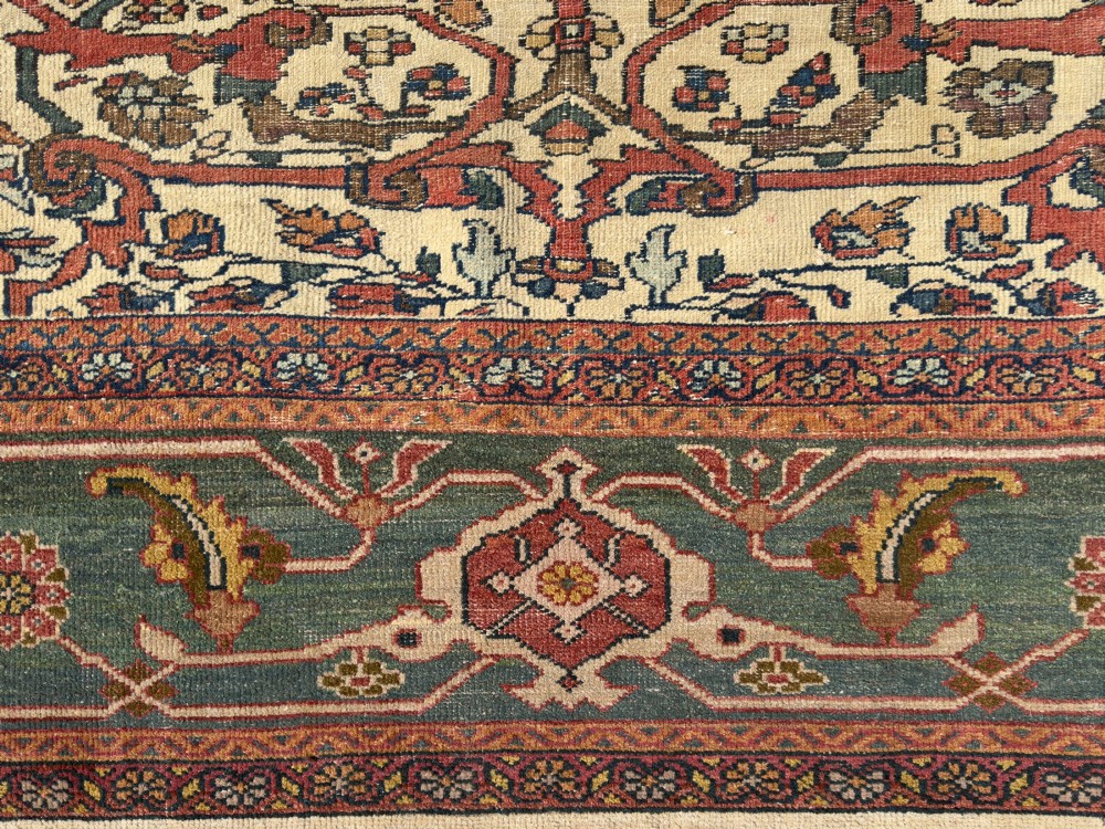 An antique Persian Sultanabad wool carpet featuring a cream field with an intricate floral lattice motif and a wide teal green border. View VI