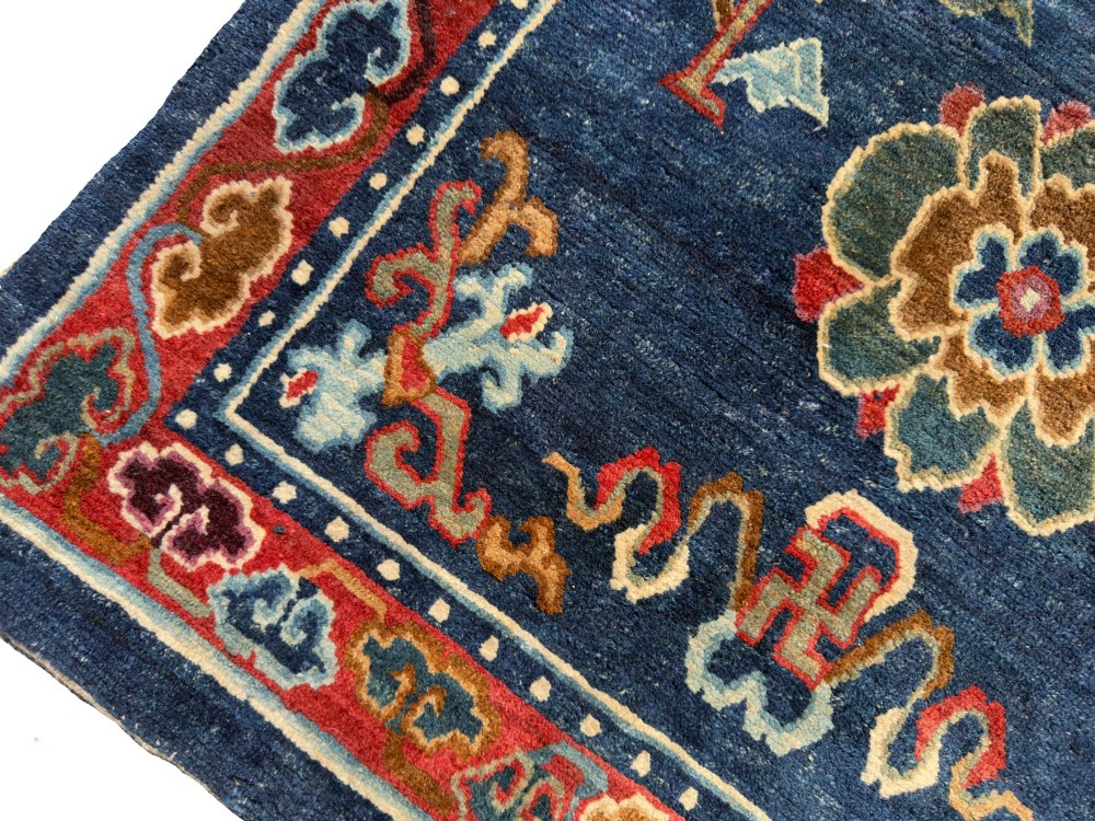 An antique hand-knotted Tibetan Khaden rug featuring a deep blue field adorned with three stylised lotus blossoms and red decorative borders. View VI
