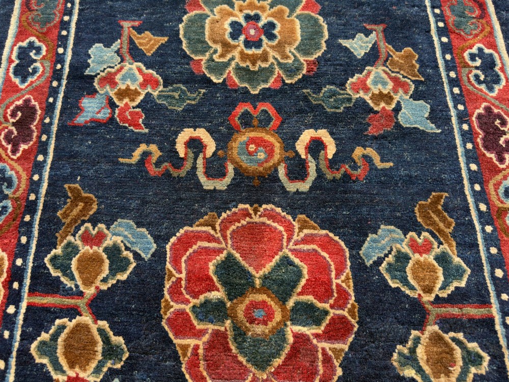 An antique hand-knotted Tibetan Khaden rug featuring a deep blue field adorned with three stylised lotus blossoms and red decorative borders. View VII