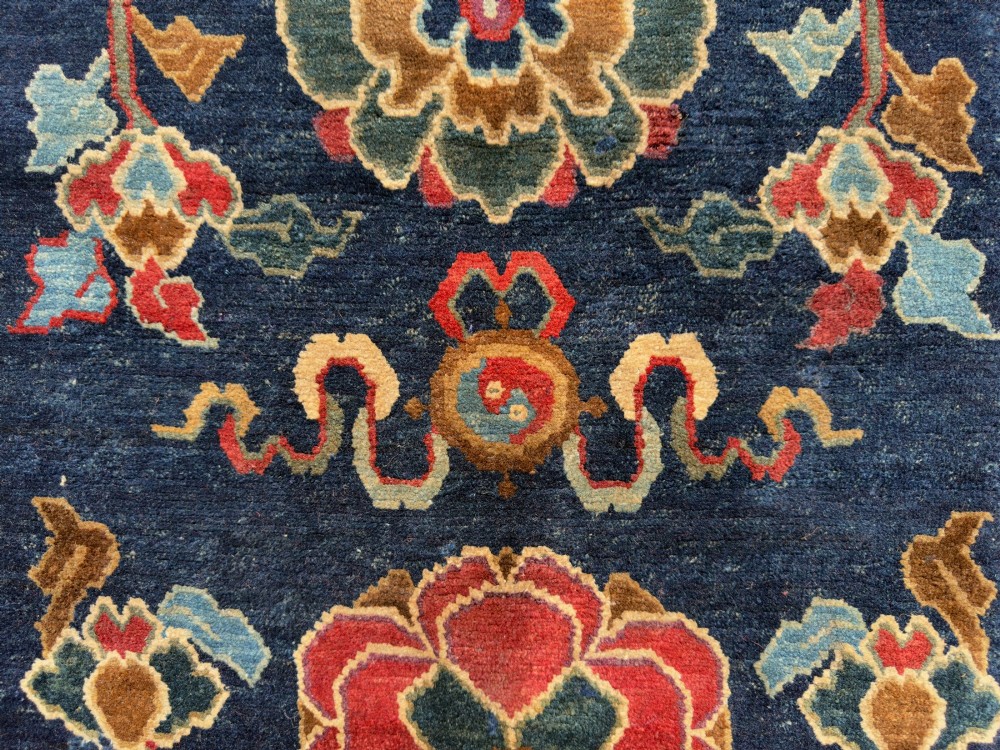 An antique hand-knotted Tibetan Khaden rug featuring a deep blue field adorned with three stylised lotus blossoms and red decorative borders. View VIII