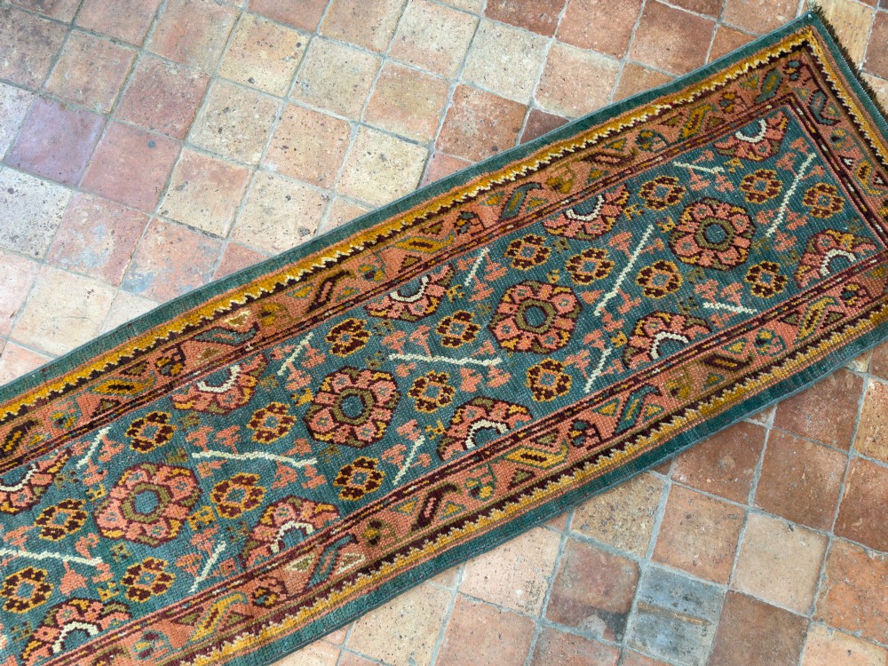 An exceptionally long antique Ushak runner rug displaying a central slate blue panel with repeating coral floral rosettes framed by a wide terracotta patterned border. View VII