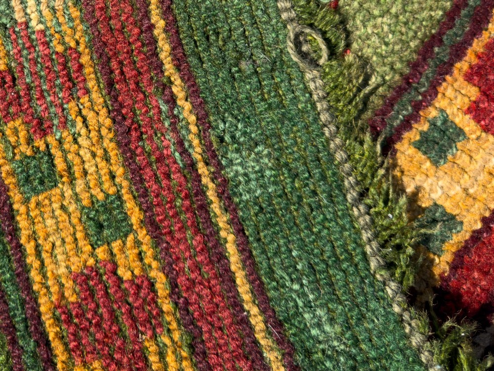 An antique Arts and Crafts hand-knotted wool Donegal carpet featuring a green field filled with stylised red and yellow floral motifs and a decorative geometric border. View VIII