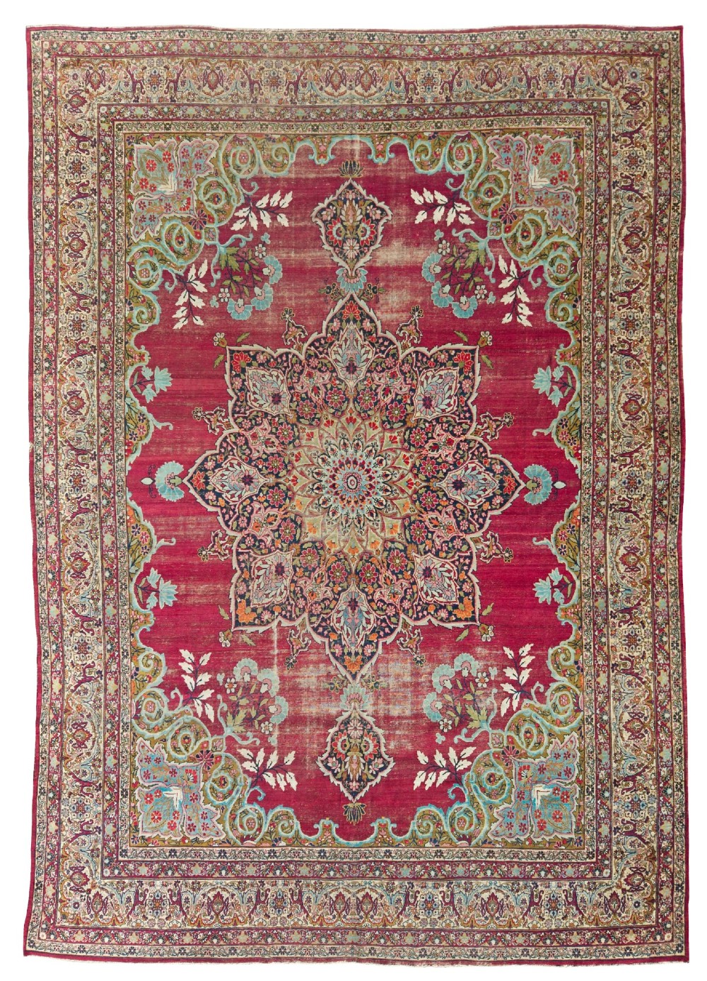 An antique hand-knotted Kirman wool carpet featuring a large central starburst medallion surrounded by floral borders on a crimson red field with distressed wear.