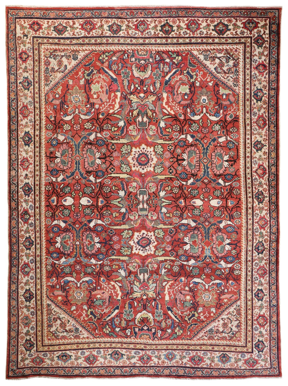 A hand-knotted antique Persian Mahal carpet featuring a terracotta red field with intricate floral motifs surrounded by cream and navy decorative borders.