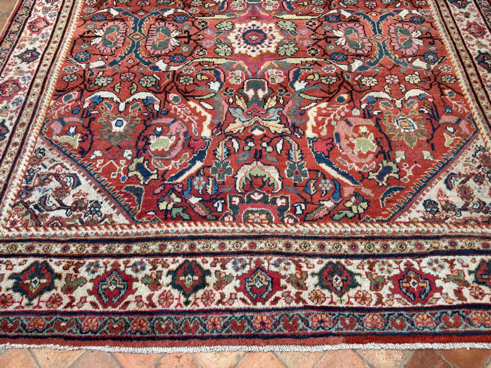 A hand-knotted antique Persian Mahal carpet featuring a terracotta red field with intricate floral motifs surrounded by cream and navy decorative borders. View IV