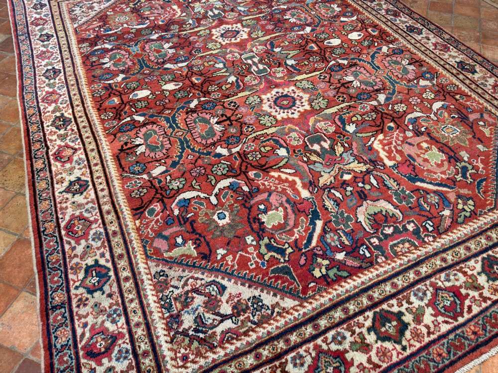 A hand-knotted antique Persian Mahal carpet featuring a terracotta red field with intricate floral motifs surrounded by cream and navy decorative borders. View V