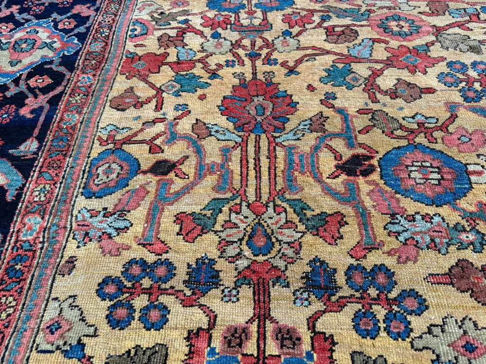 An antique Farahan Persian wool carpet with a yellow floral field framed by a dark navy decorative border. View II