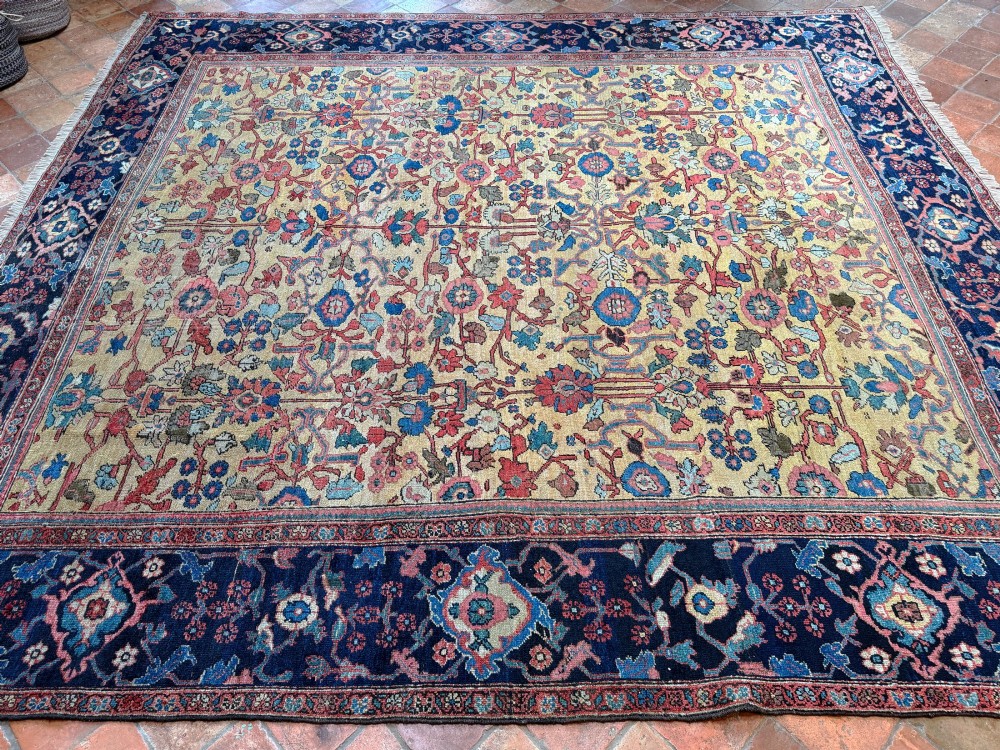 An antique Farahan Persian wool carpet with a yellow floral field framed by a dark navy decorative border. View IV