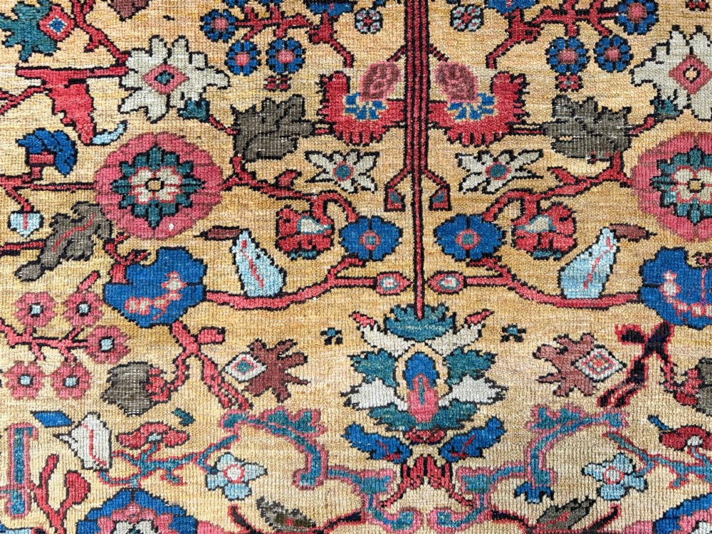 An antique Farahan Persian wool carpet with a yellow floral field framed by a dark navy decorative border. View VI