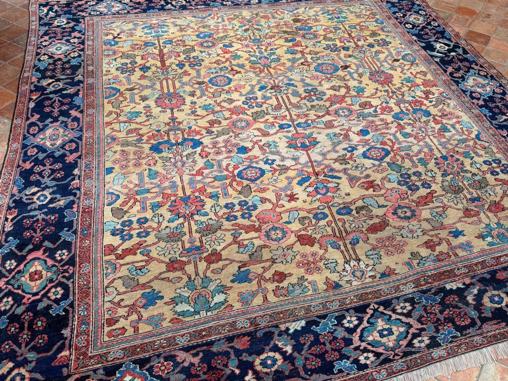 An antique Farahan Persian wool carpet with a yellow floral field framed by a dark navy decorative border. View VIII