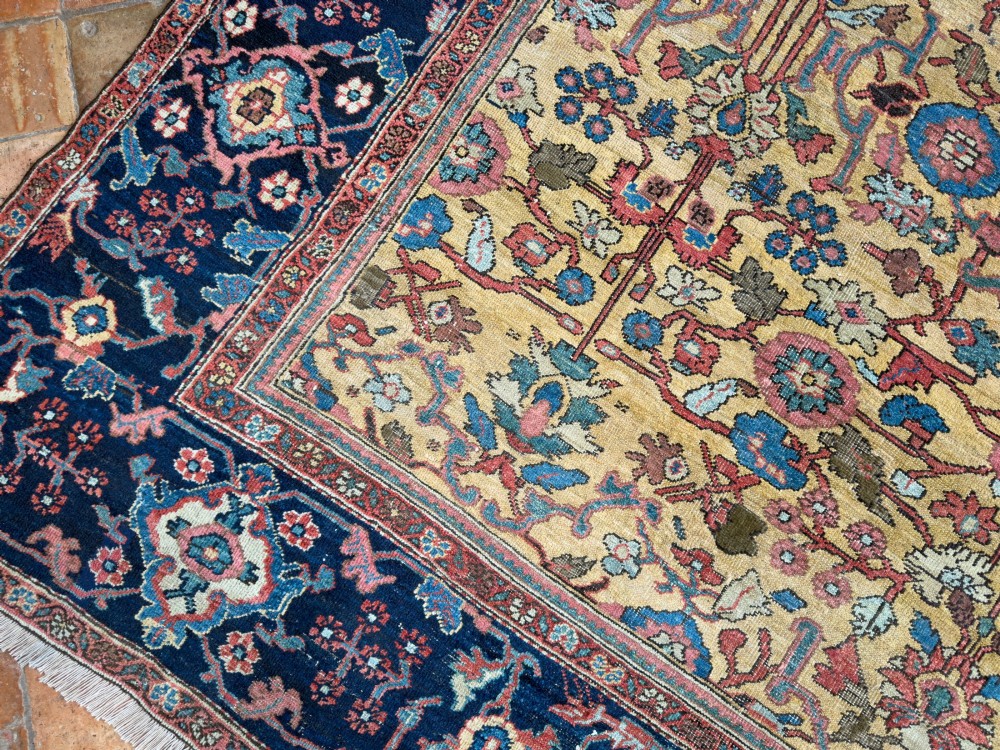 An antique Farahan Persian wool carpet with a yellow floral field framed by a dark navy decorative border. View XI