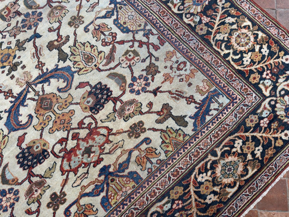 An antique hand-knotted Persian Mahal carpet featuring an ivory ground decorated with intricate floral vines and framed by a dark navy decorative border. View IV