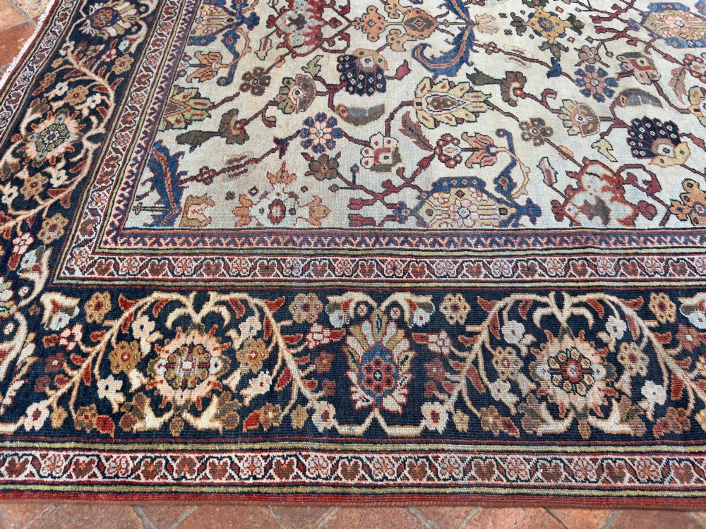 An antique hand-knotted Persian Mahal carpet featuring an ivory ground decorated with intricate floral vines and framed by a dark navy decorative border. View VI