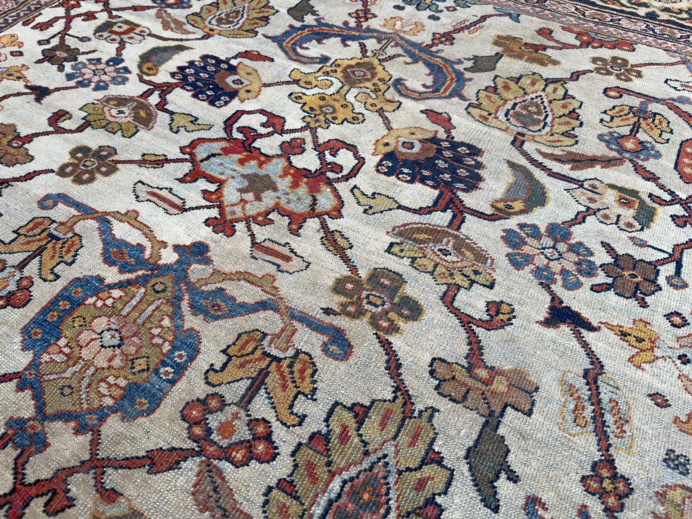 An antique hand-knotted Persian Mahal carpet featuring an ivory ground decorated with intricate floral vines and framed by a dark navy decorative border. View VII