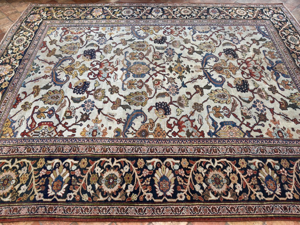 An antique hand-knotted Persian Mahal carpet featuring an ivory ground decorated with intricate floral vines and framed by a dark navy decorative border. View IX
