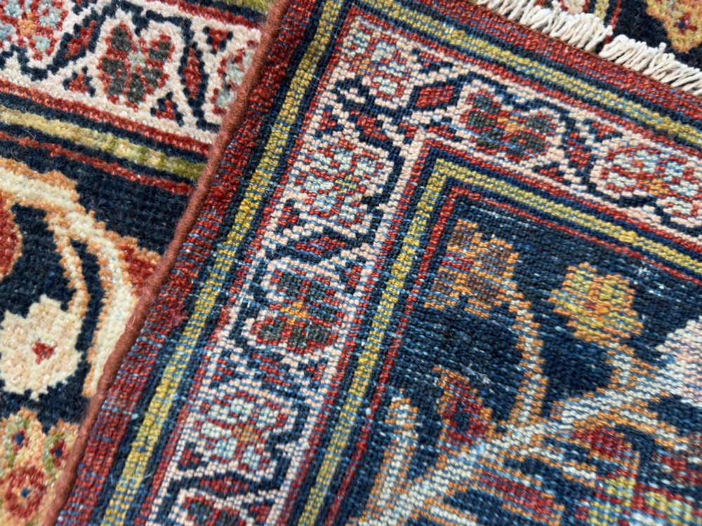 An antique hand-knotted Persian Mahal carpet featuring an ivory ground decorated with intricate floral vines and framed by a dark navy decorative border. View X