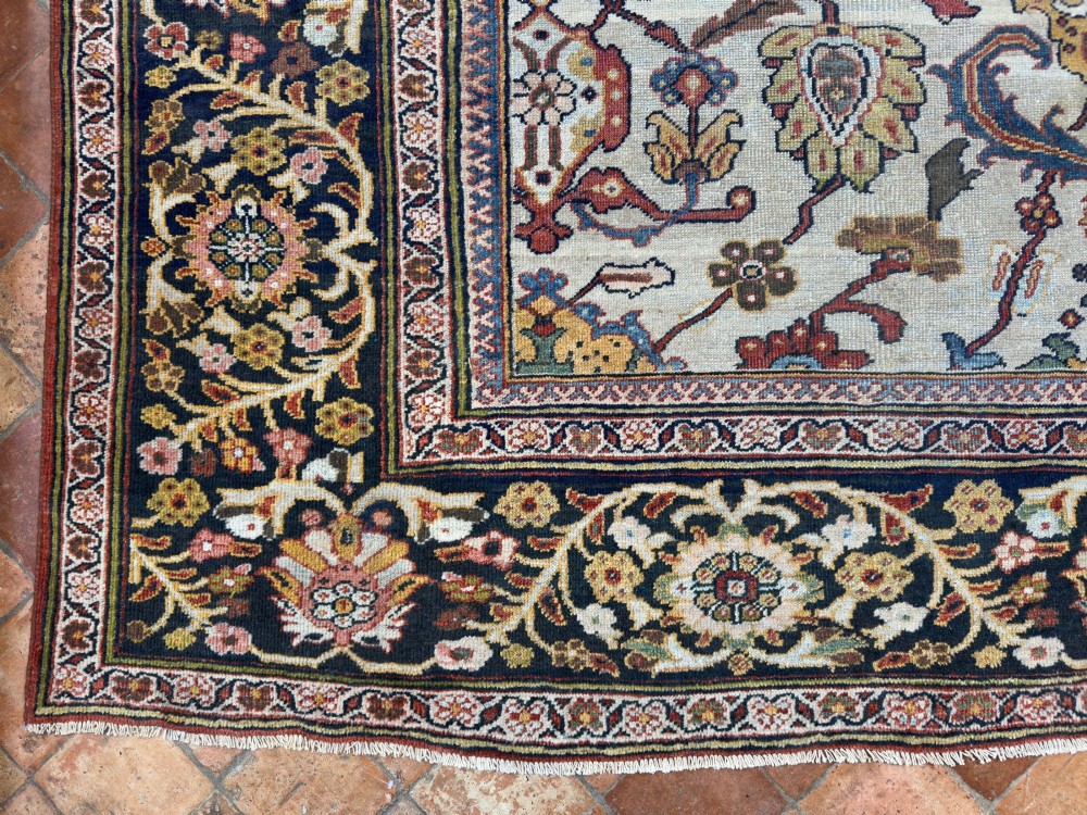 An antique hand-knotted Persian Mahal carpet featuring an ivory ground decorated with intricate floral vines and framed by a dark navy decorative border. View XII