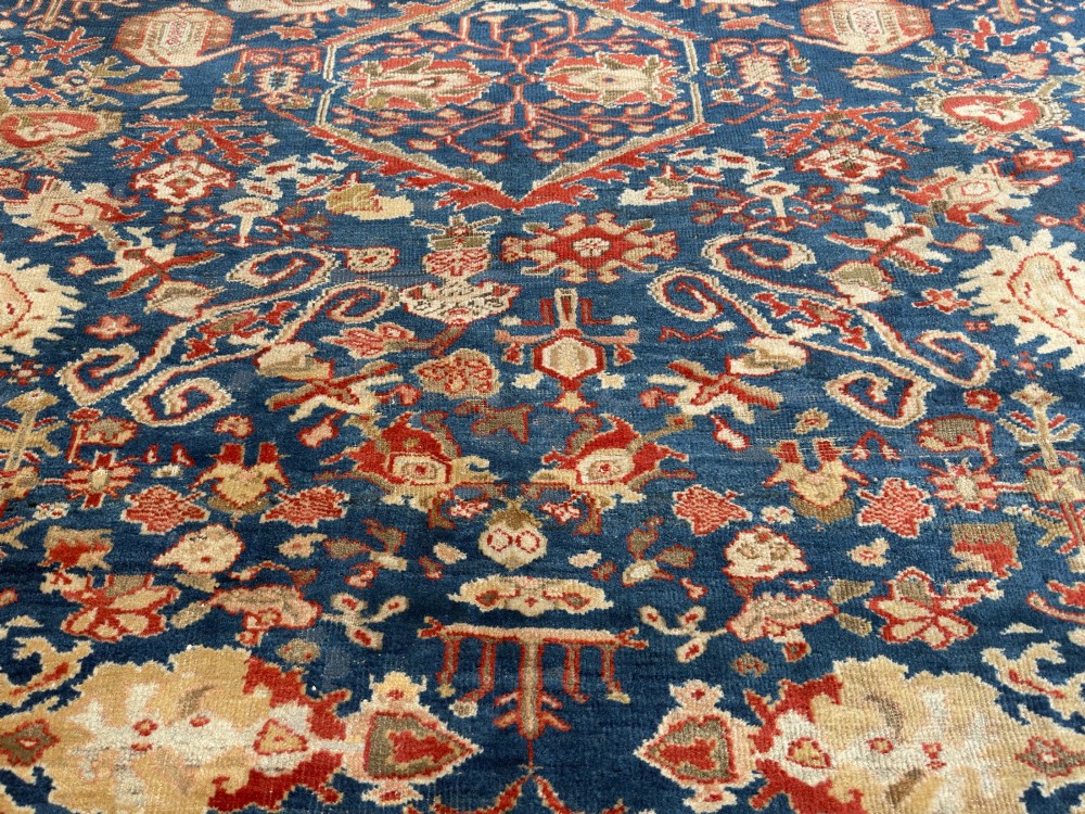 An antique hand-knotted Persian Ziegler carpet featuring a deep indigo blue central field decorated with ivory and terracotta floral motifs inside a wide terracotta border. View III