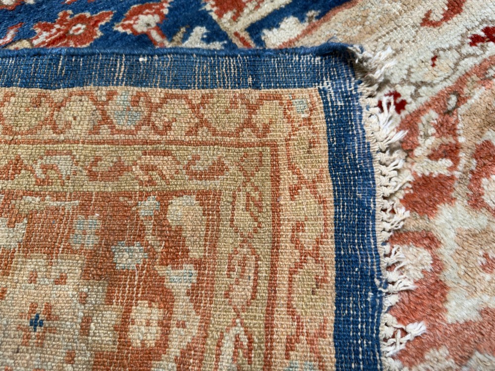 An antique hand-knotted Persian Ziegler carpet featuring a deep indigo blue central field decorated with ivory and terracotta floral motifs inside a wide terracotta border. View VIII