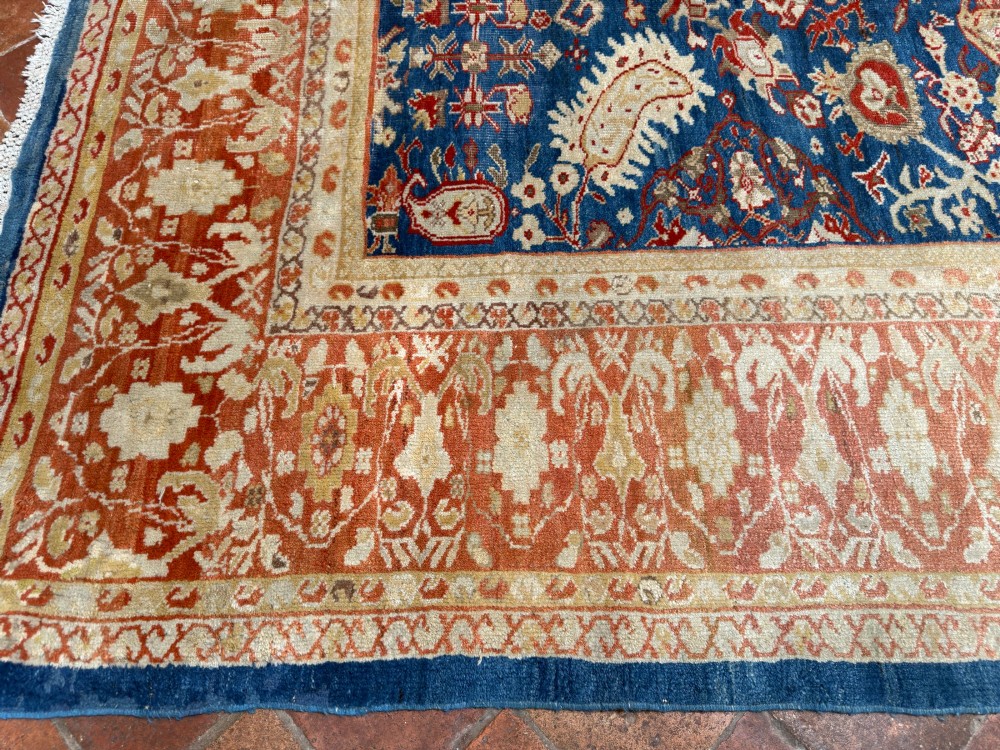 An antique hand-knotted Persian Ziegler carpet featuring a deep indigo blue central field decorated with ivory and terracotta floral motifs inside a wide terracotta border. View IX