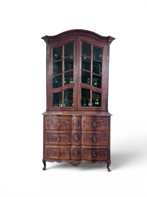 fig 1. An 18th-century French dark oak two-piece cabinet featuring a carved commode base with brass handles beneath an arched glazed vitrine top.
