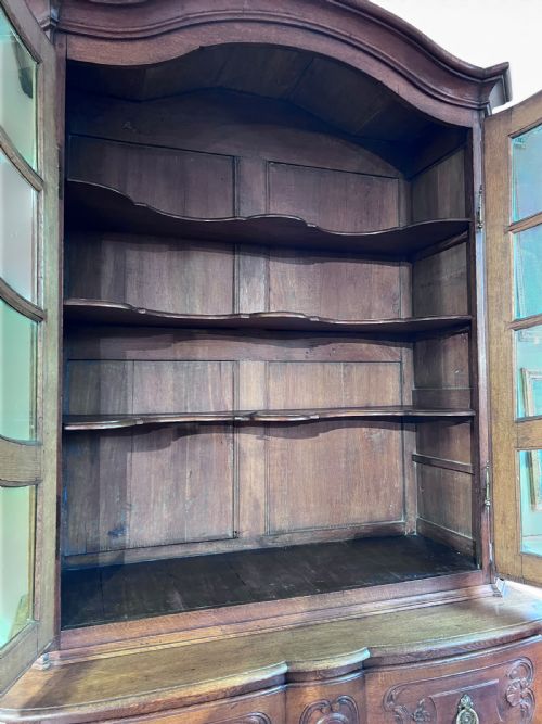 fig 2. An 18th-century French dark oak two-piece cabinet featuring a carved commode base with brass handles beneath an arched glazed vitrine top.